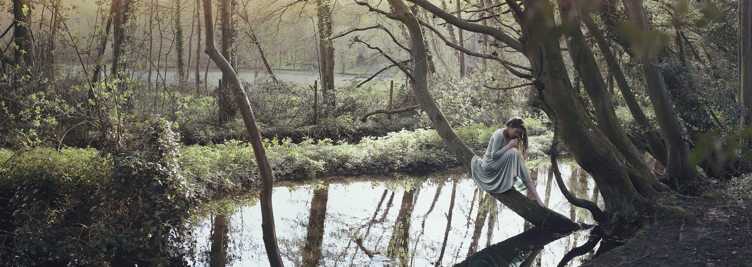 The memory of trees. Girl dresswith a princess dress by the stream. Sunset in the back. Fairytale mood. Silvia Travieso