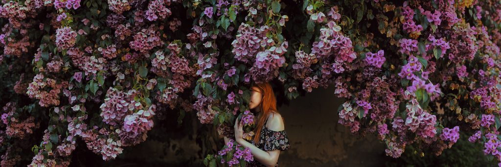 She hides behind a buganvilla purple flowers, cuteness yet fire. Delicate romantic. Silvia Travieso
